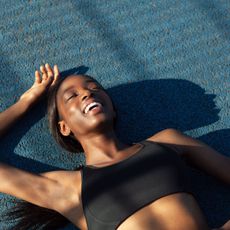 A woman lying down on the ground having done one of the best core workouts with weights