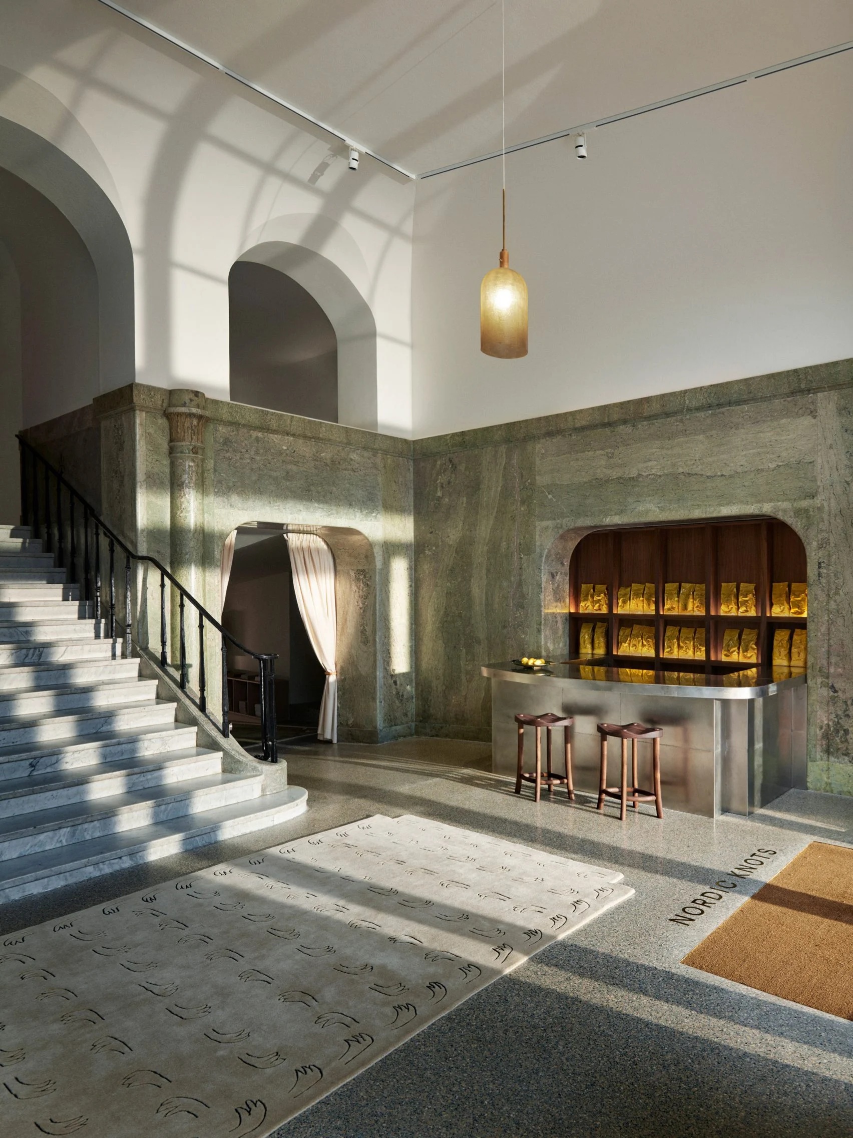 A sumptuous design atelier, housed within a palatial, terrazzo floors, marble, and stucco-clad villa, boasts a pastel-shaded color palette of muted greens, ochre, wood notes, and chrome.