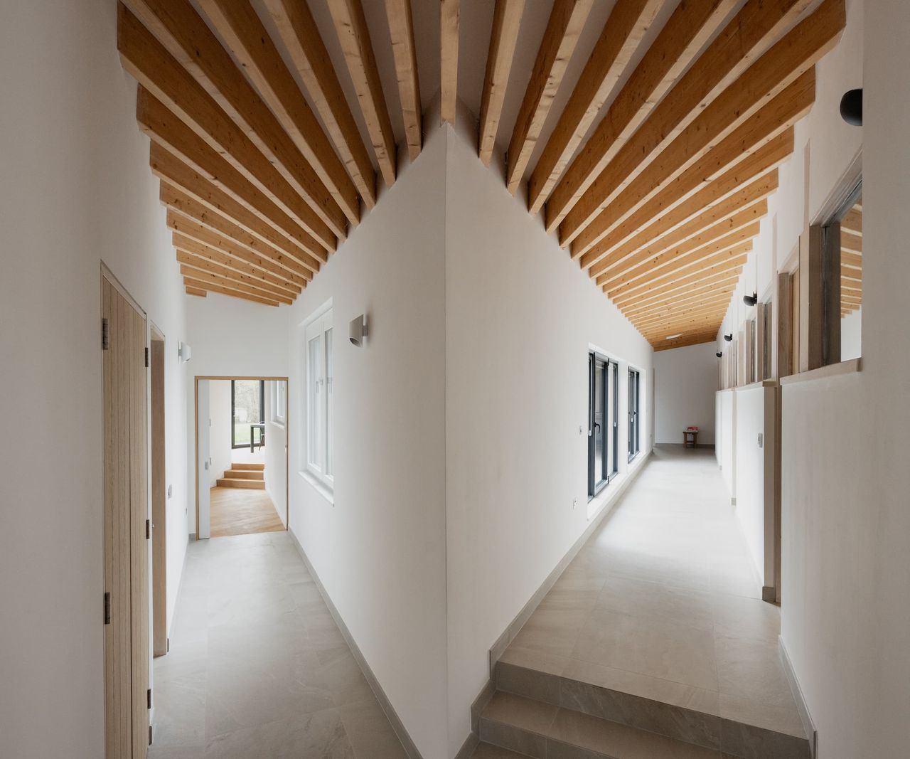 A hallway with wooden beams above and connected hallways going in different directions