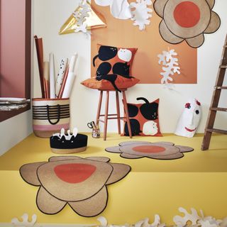 A selection of colorful home decor items, including throw pillows, flower-shaped rugs, and woven baskets