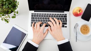 Hands typing on a laptop