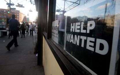 A help wanted sign hangs in a window