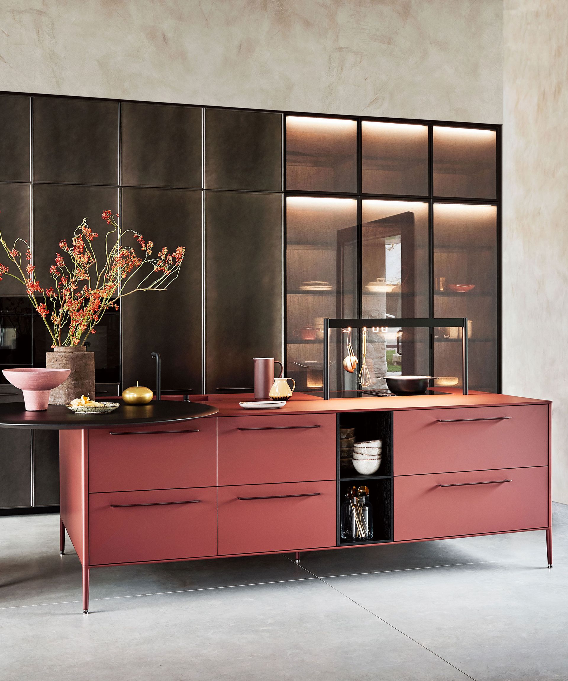 An example of modern kitchen lighting ideas showing a pink island in front of black floor to ceiling kitchen cabinets