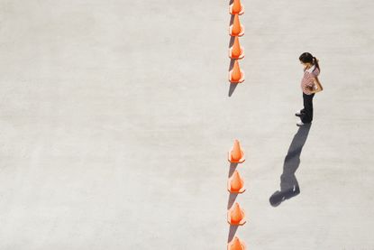 Woman looking at row of traffic cones with gap
