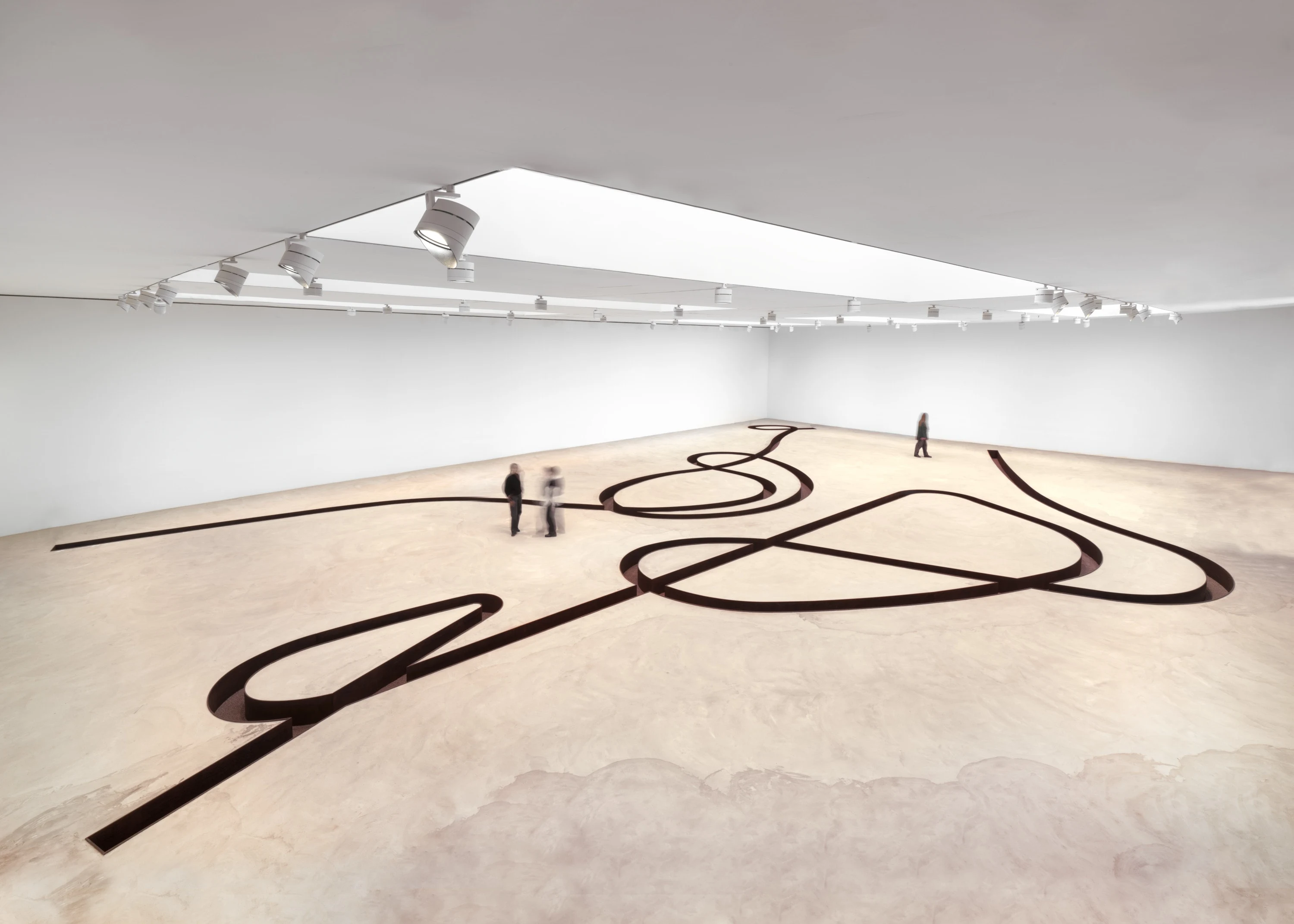 An installation called Negative Sculpture by land artist Michael at the Gagosian, where a steel-lined trench winds across a concrete floor surrounded by a white gallery space.