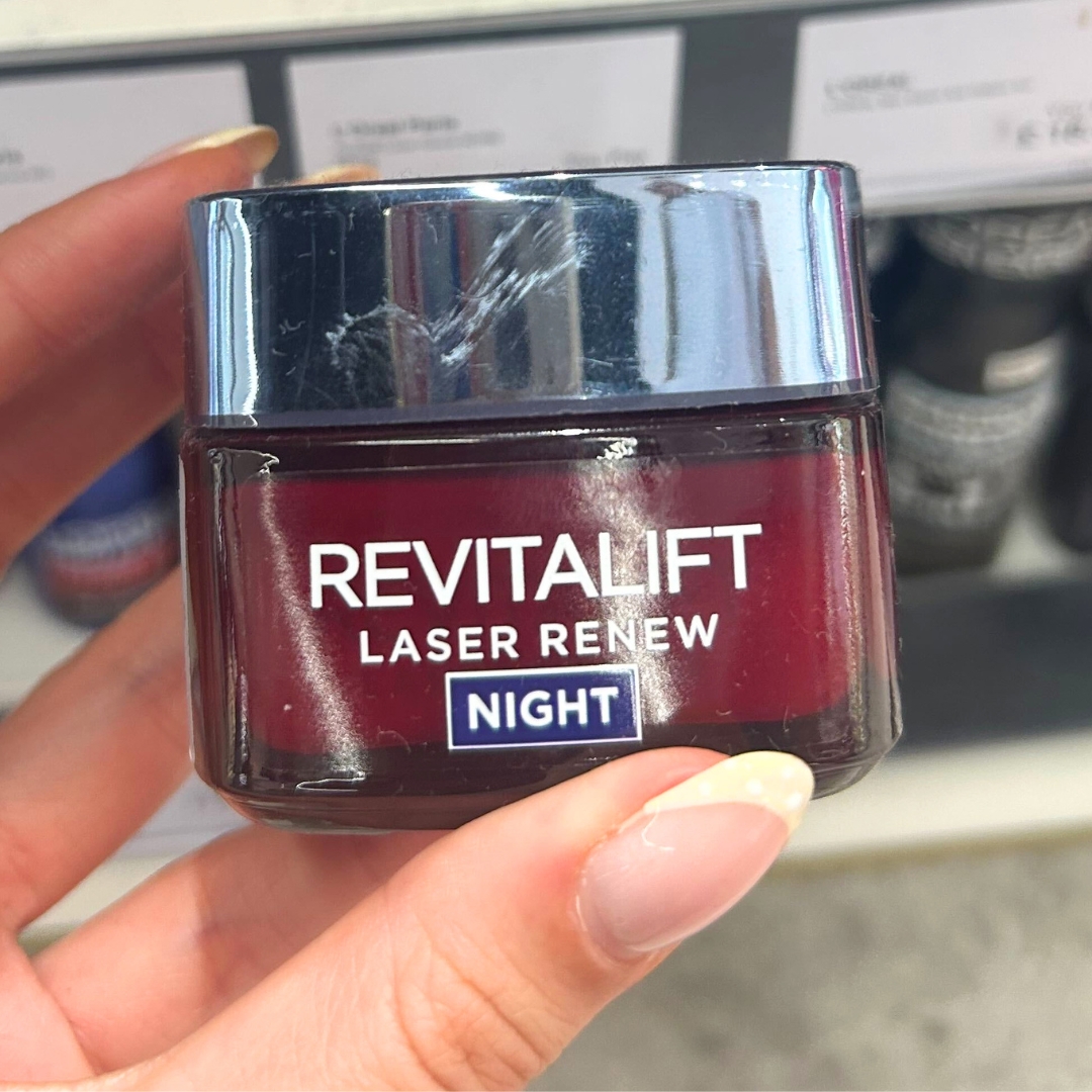 Hand holding tub of L'Oreal Revitalift Laser Night Cream in World Duty Free