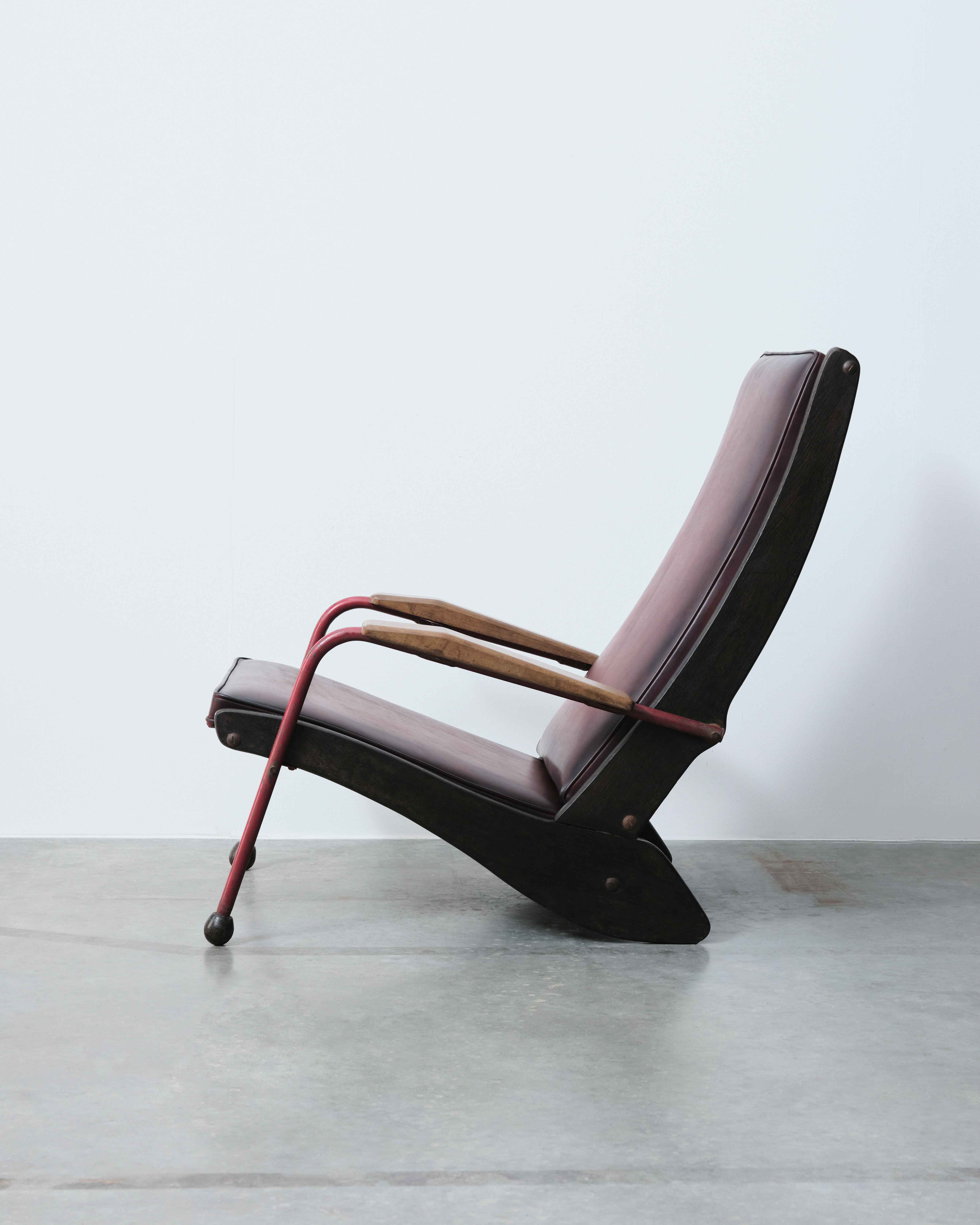 Chair by Jean Prouve photographed from the side on a concrete floor