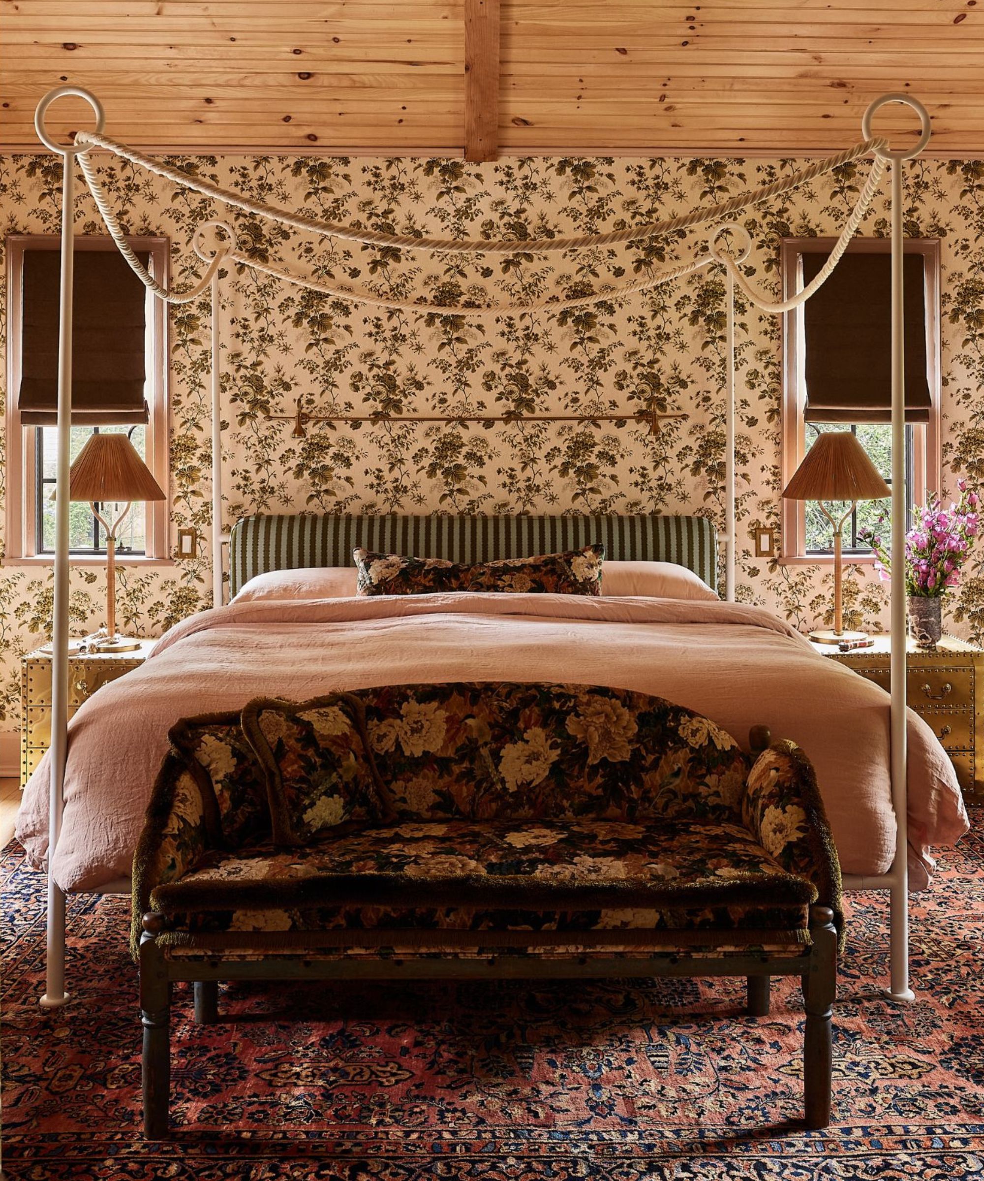 a wallpapered floral bedroom with a canopy bed and a pine clad ceiling