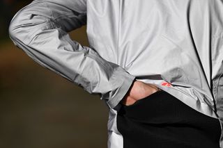 Close-up of a rider's left hand reaching through the slit in the back of the Tempesta Lite jacket to reach his jersey pockets