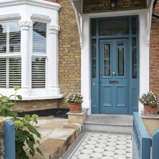 house with blue wooden door brick walls and white windows