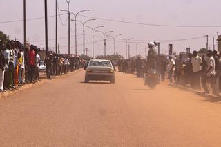The caravan rolls through the dusty streets of Ouagadougou ahead of the peloton.