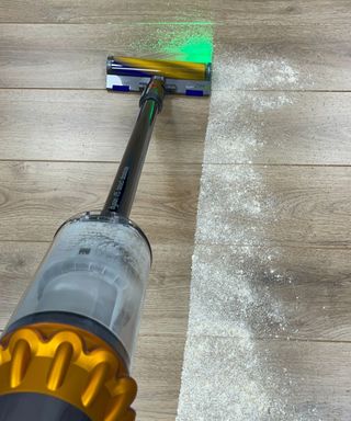 Dyson V15 Detect vacuuming a line through flour and sugar on wooden floor in Future test center