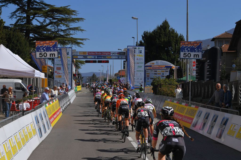 The peloton rides through the start/finish line