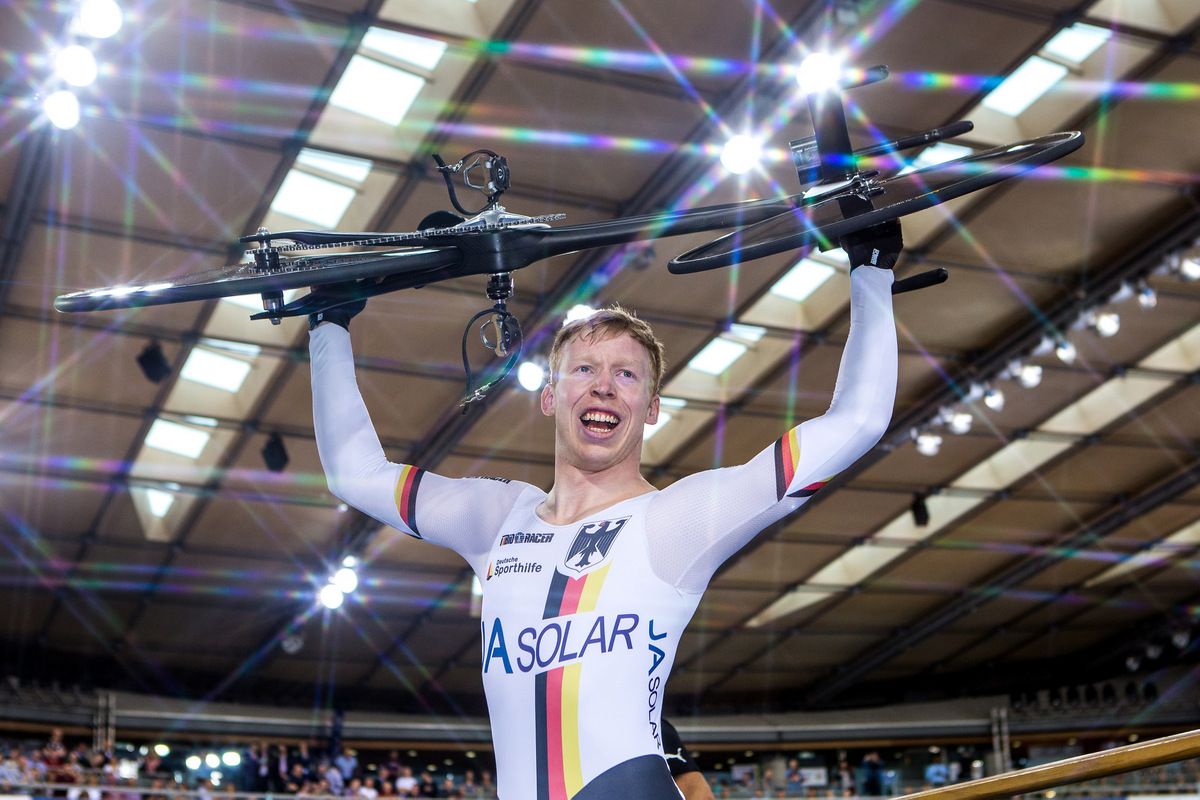 Joachim Eliers holds his bike in the air to celebrate his win in the kilo