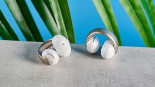 Soundcore AeroClip open-ear earbuds in champagne mist against a blue backdrop