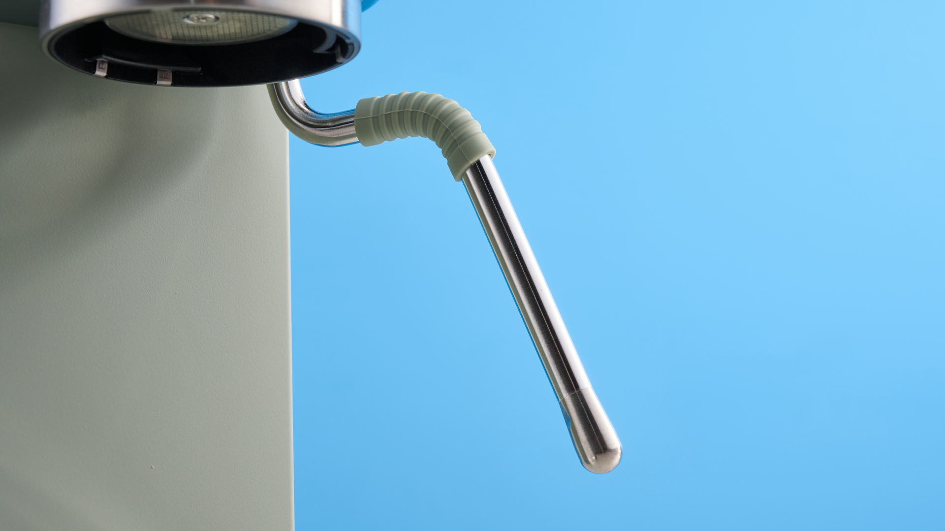 Steam wand of the DeLonghi Dedica Duo in the green colorway photographed on a blue background.