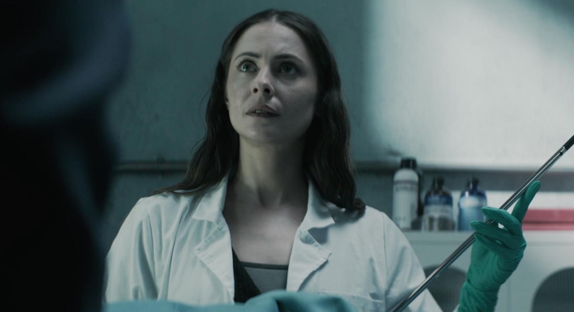 Willa Holland as Rebecca Owens in The Mortuary Assistant, holding a long needle