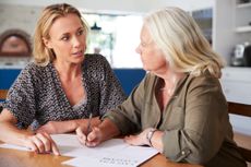 A young woman helps an older woman write her will as part of estate planning.