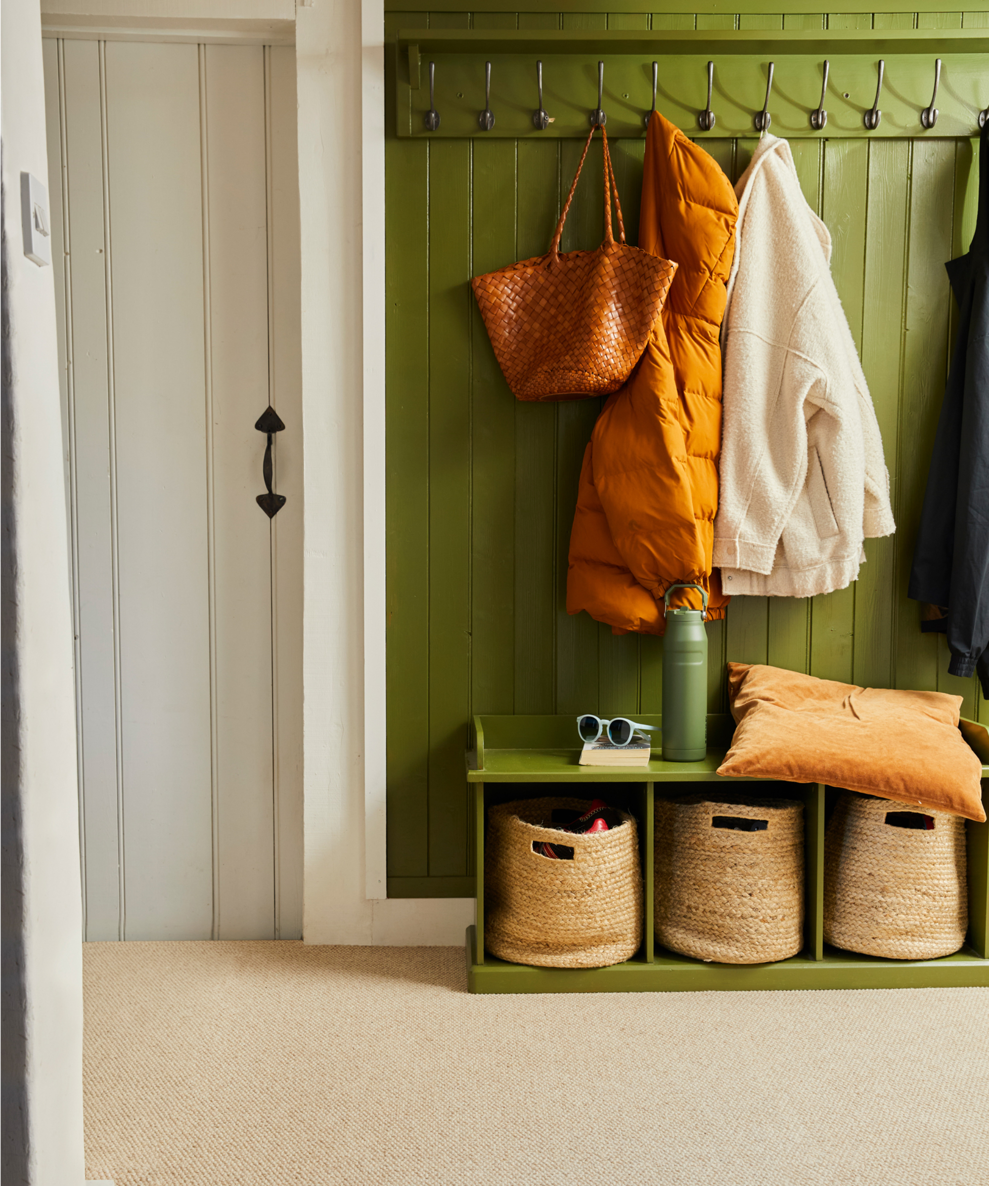 oatmeal carpet in hallway with green panelled wall with boot room style storage
