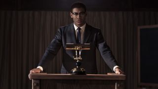 Aaron Pierre as Malcolm X behind a podium in Genius: MLK/X episode 4