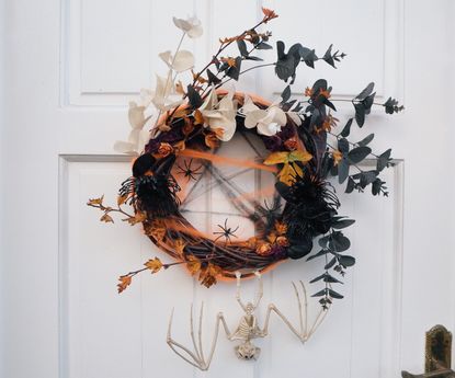 halloween wreath with spiders, skeleton, faux and real stems on white front door 