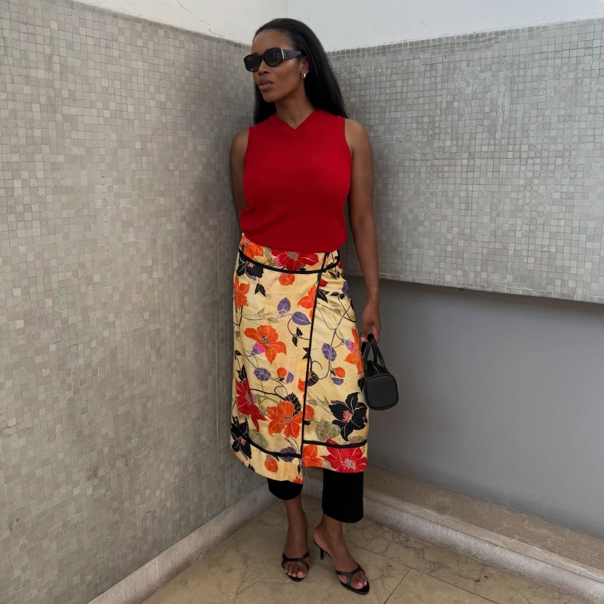 Woman wears red tank top, floral skirt, black heels