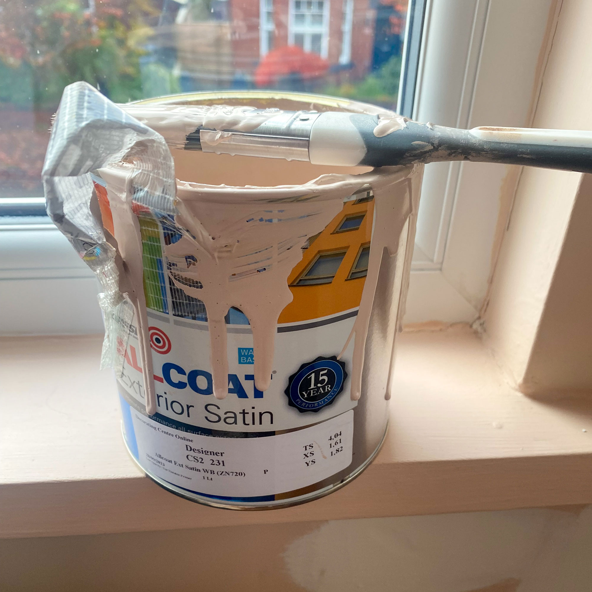 Open and used can of paint with brush resting on top