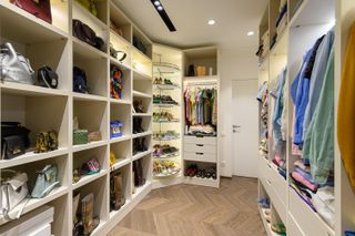 A large walk in closet with shelving for bags and purses