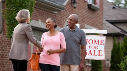 Senior couple buying or selling a house shaking hands with Realtor