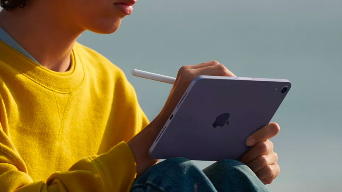 A woman uses an iPad sat on the beach