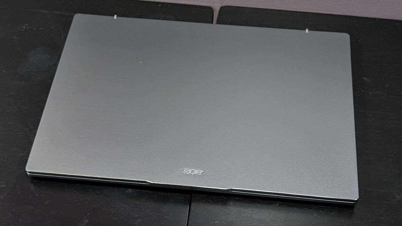 A gray laptop with its lid closed sitting on top of a black surface.