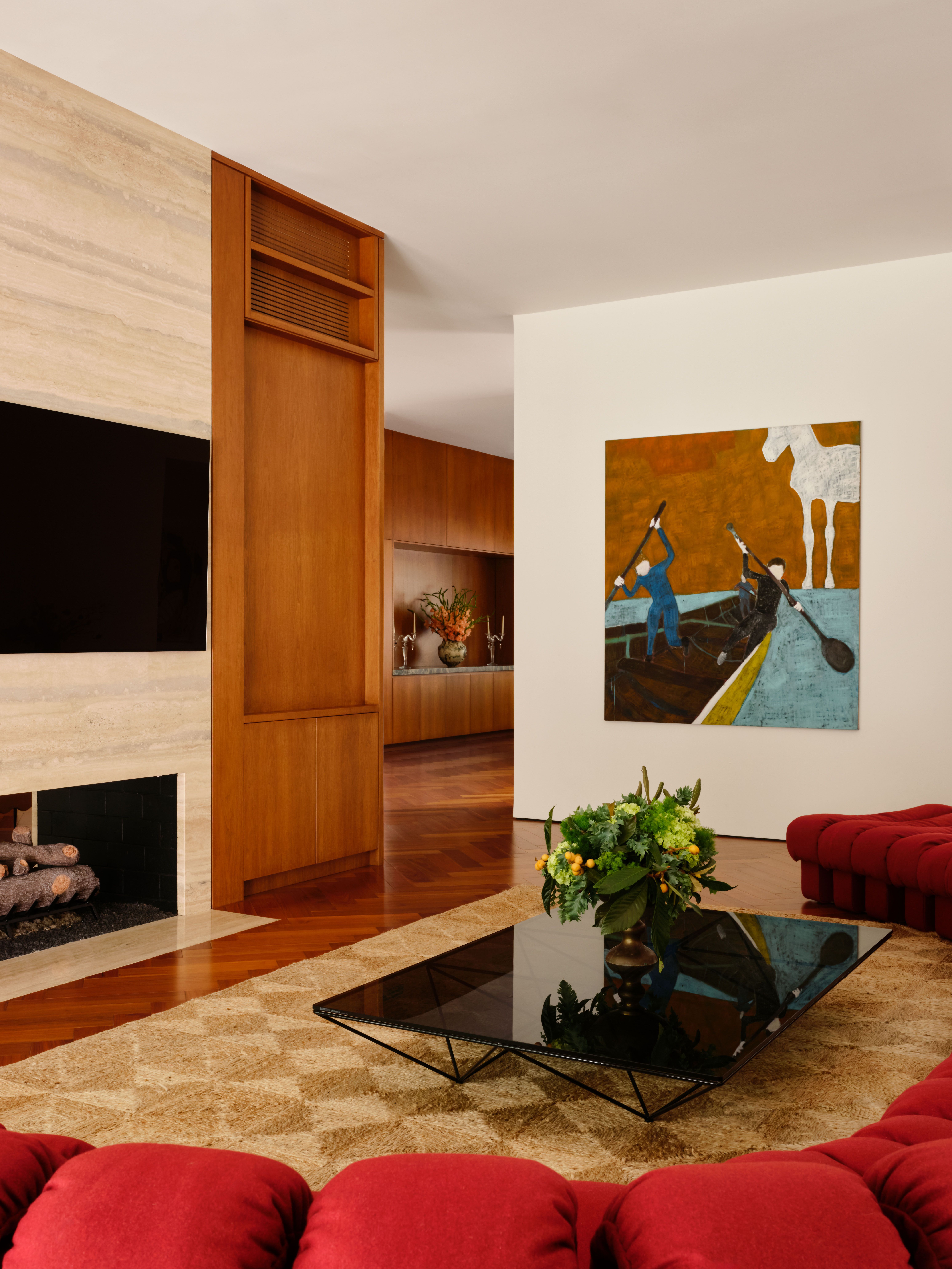 Living with a modular red sofa in velvet, a beige checkered rug, and a glossy coffee table, from which you can catch a view of the dining room