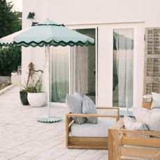 Business & Pleasure Co. Molded Parasol Stand in sage on a patio of a modern white-painted house