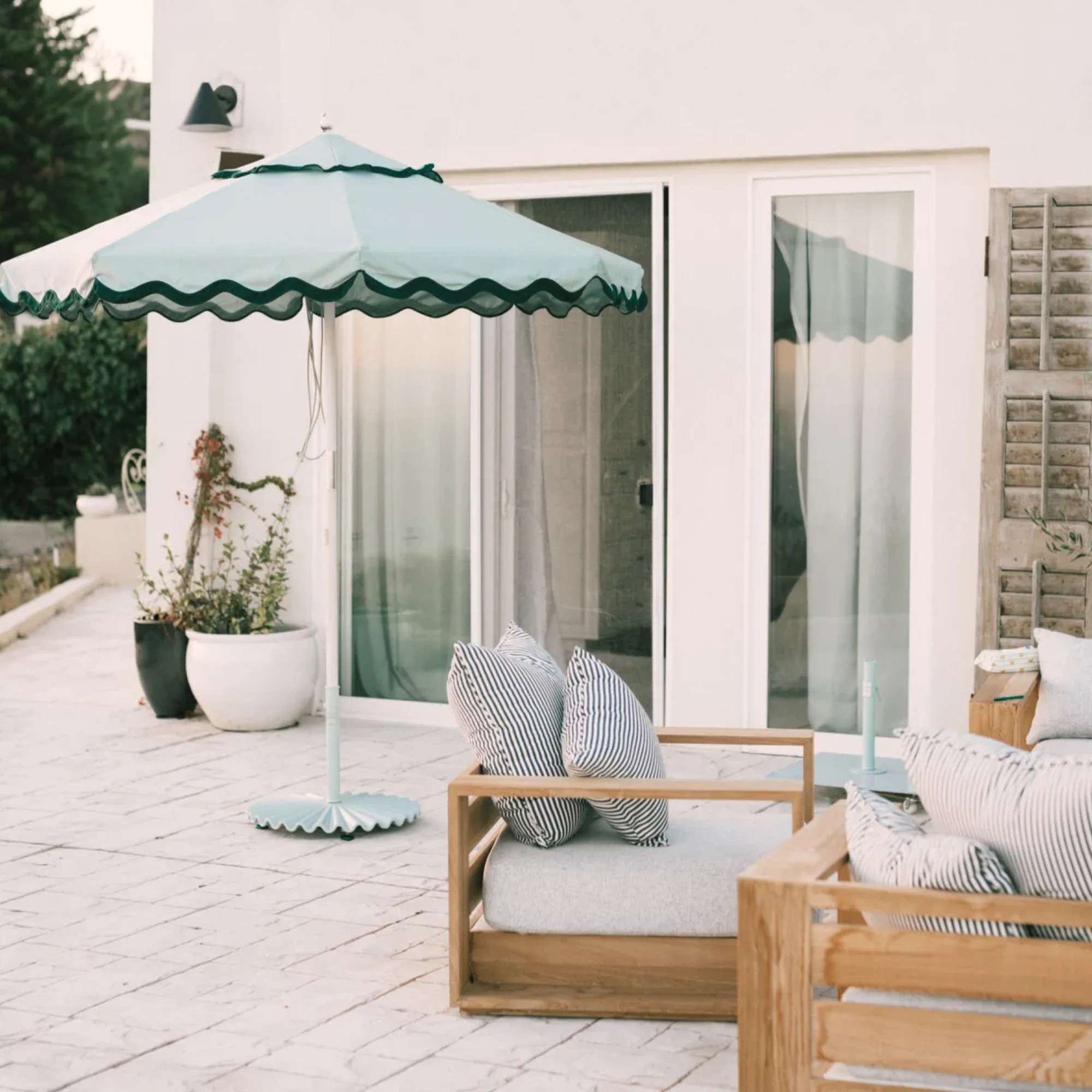 Business &amp; Pleasure Co. Molded Parasol Stand in sage on a patio of a modern white-painted house
