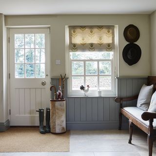 boot room with white and grey wall and wooden floor and white door and window