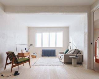 minimalist living room with plaster walls and grey sofa with iron radiator