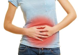 A woman grips her abdomen in pain. 