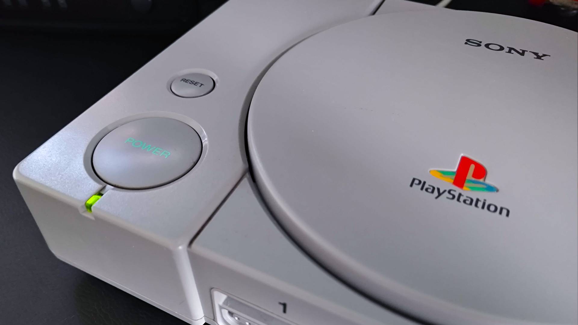 Close up of PS1 console with green power light on.