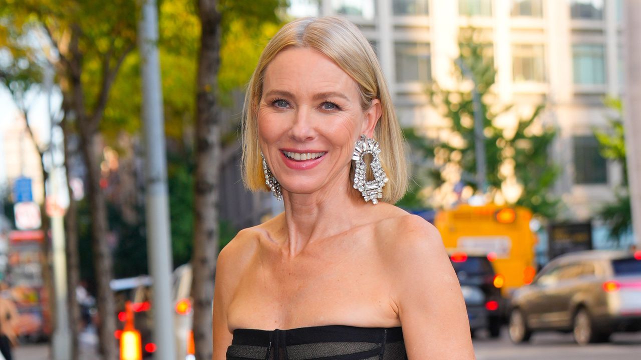 Naomi Watts wears a sheer black strapless top as has silver earrings in the shape of keyholes and a short blonde bob