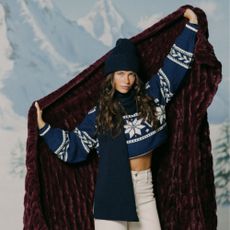 Young brunette woman holding Lola Blanket with snowy mountains as backdrop