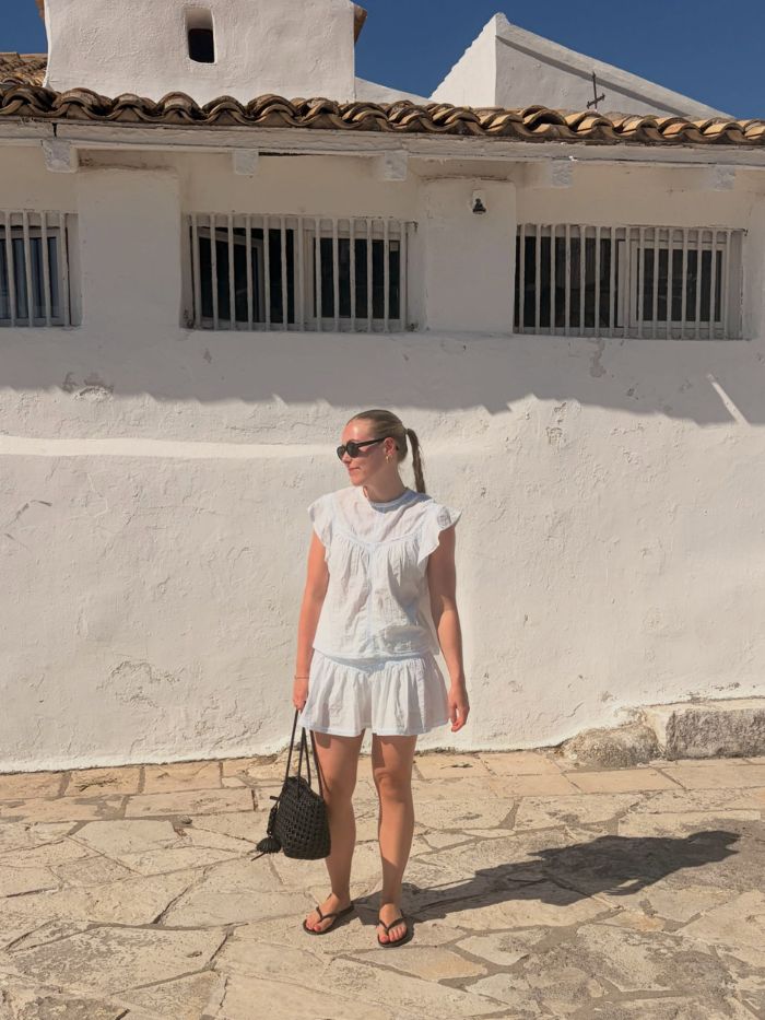 Woman wears white blouse, matching white skirt