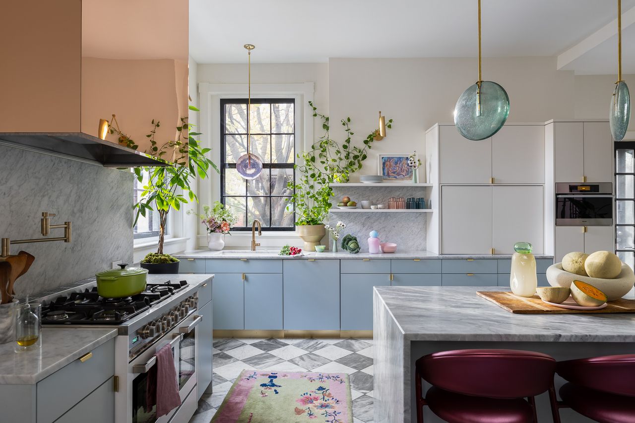The kitchen sports pastel blue cabinets, painted floor tiles, a mirror acrylic hood surround and a pastel blue island light