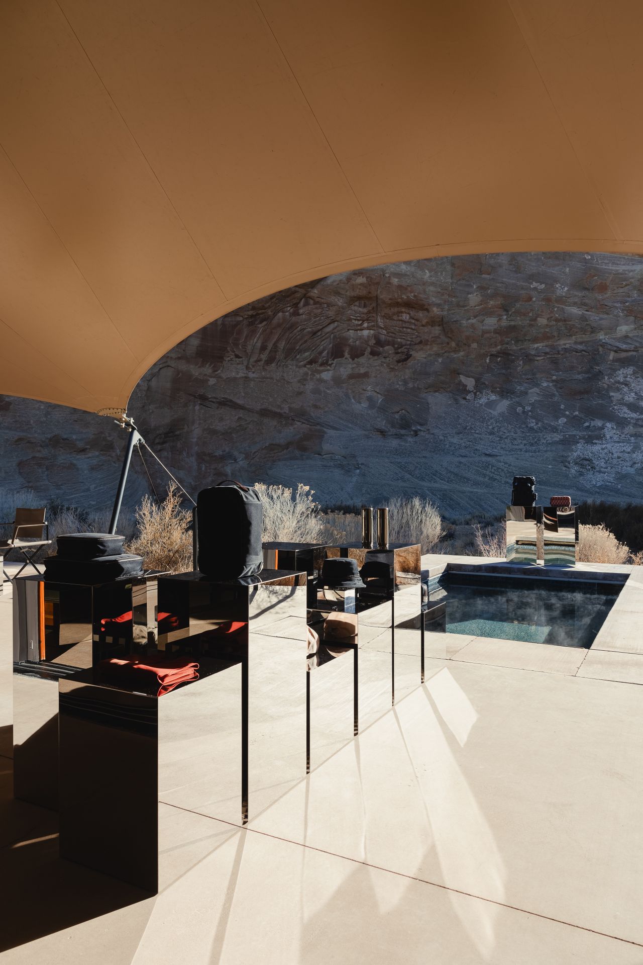 The offering of a sleek hotel gift shop is set up among the dramatic mountain range of Utah's desert, nestled either within a camel tent decorated with sophisticated, reflective furniture, or en-plain-air in dialogue with the outdoors.