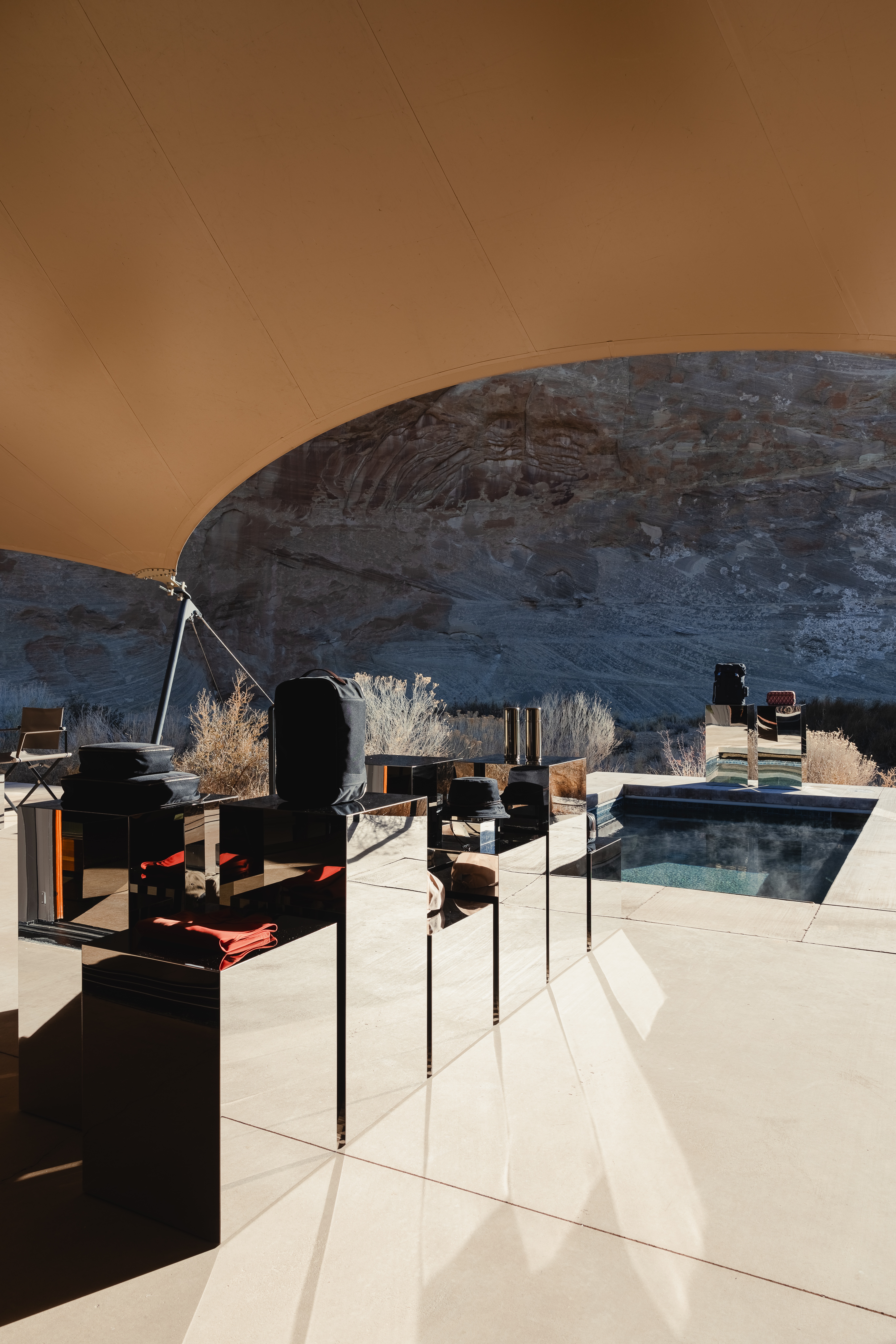 The offering of a sleek hotel gift shop is set up among the dramatic mountain range of Utah's desert, nestled either within a camel tent decorated with sophisticated, reflective furniture, or en-plain-air in dialogue with the outdoors.