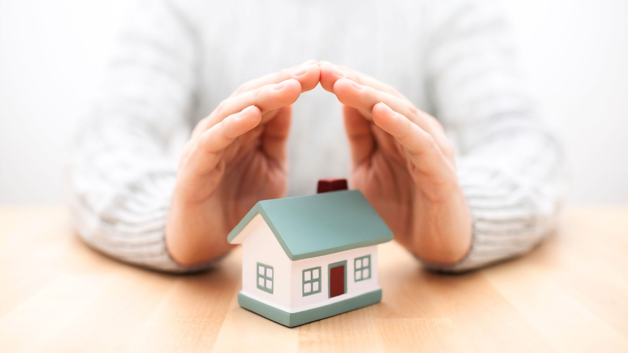 A person's hands covering a model home 