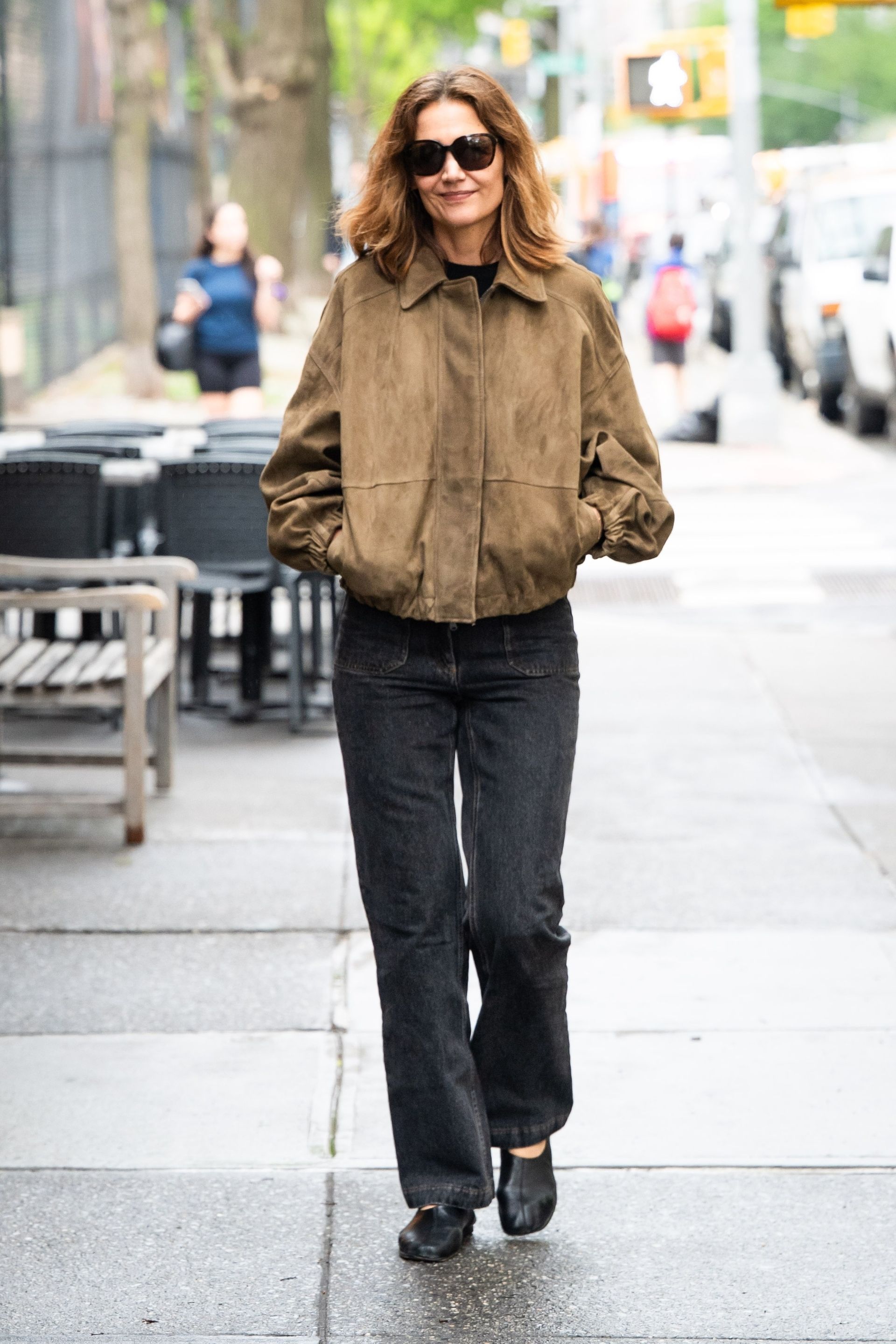 Katie Holmes wears a suede jacket, front-patch pocket jeans, and ballet flats.