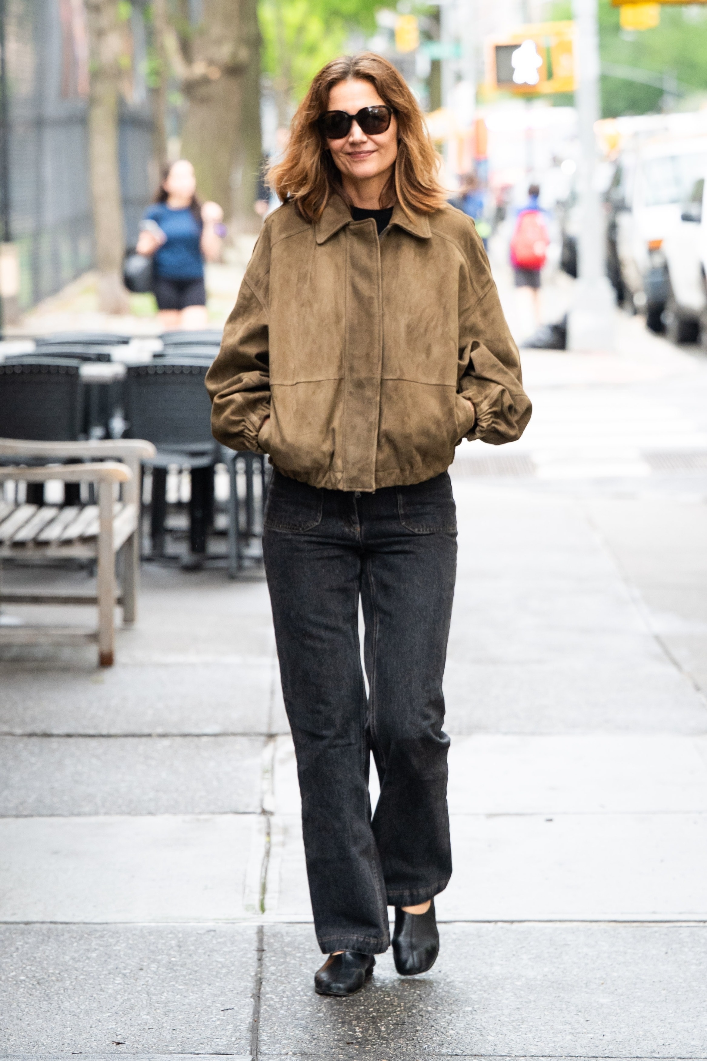 Katie Holmes wears a suede jacket, front-patch pocket jeans, and ballet flats.