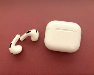 Apple AirPods (3rd Gen) beside their charging case while being tested in writer's home