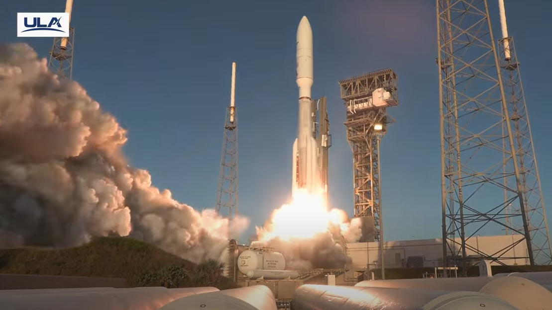 A rocket lifts off next to a puff of smoke.