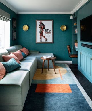 Dark green living room ideas with turquoise textured wallpaper, built-in wall storage and a squared off sectional with pink and blue cushions.